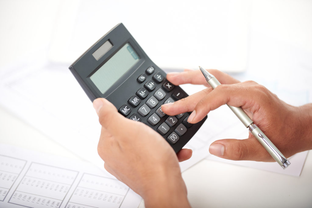 Man uses calculator to determine cost of outsourcing clinical pharmacy services