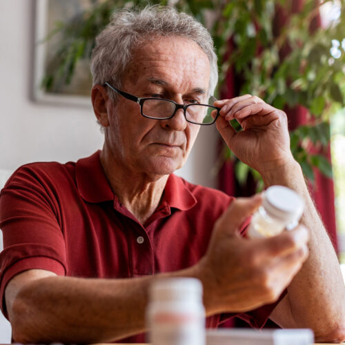 Older man reading prescription bottle information