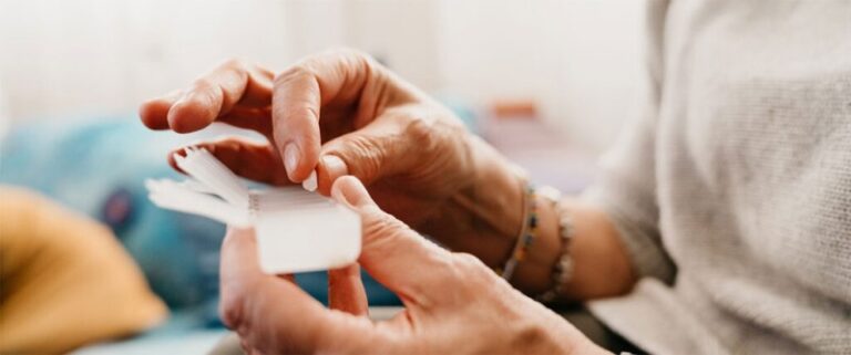 elderly patient taking pill out of pillbox.